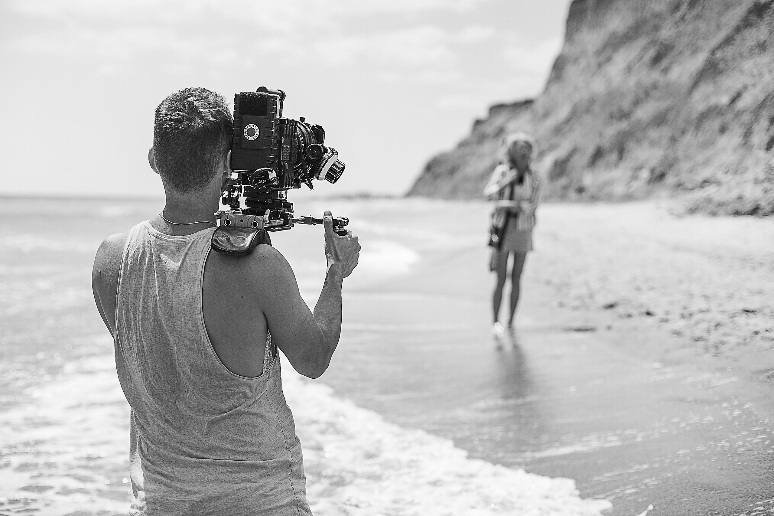Film and commercial — Videographer filming an interview setup with a shoulder-mounted camera