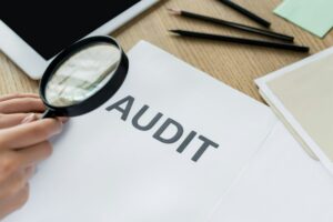 cropped view of woman holding magnifier near audit document