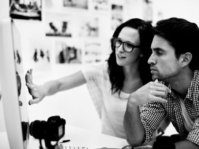 Two young photographers looking at photos on a digital camera in their studio.